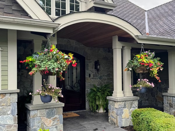 Welcoming entrance with vibrant floral arrangements framed by natural stone, creating an inviting atmosphere.