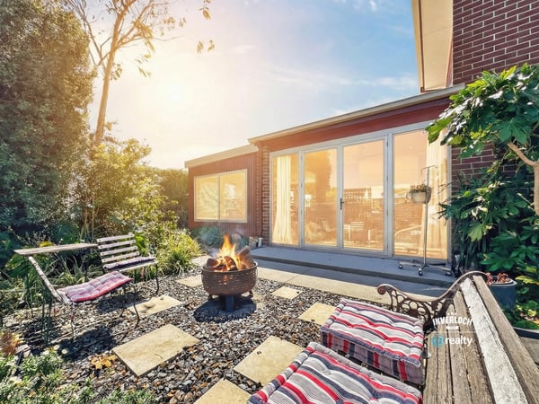 Enjoy outdoor gatherings in this inviting backyard, complete with a cozy fire pit and lush greenery.