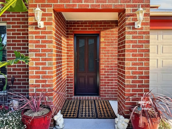 Discover a welcoming entryway framed by vibrant greenery and warm brick accents, perfect for inviting guests.