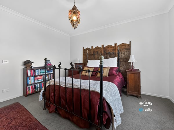 Cozy bedroom featuring a unique wooden headboard, warm lighting, and an inviting atmosphere for relaxation.