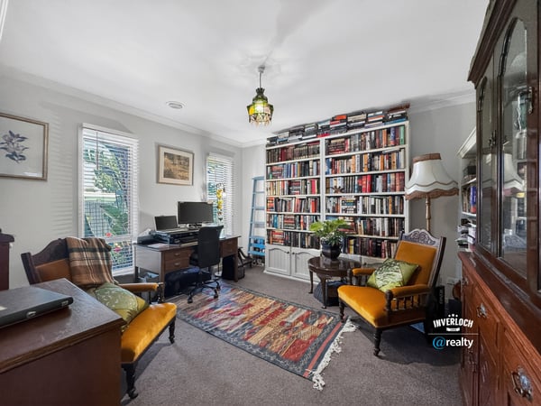 Cozy home office featuring a large built-in bookshelf, natural light, and comfortable seating for productivity.