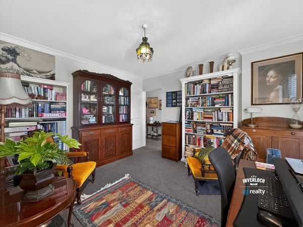 Cozy home office with built-in bookshelves, vintage furnishings, and ample natural light for productivity.