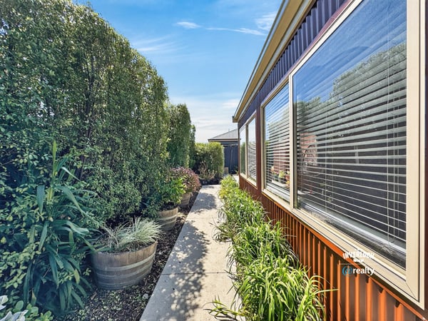 Discover a vibrant pathway lined with lush greenery, leading to inviting outdoor spaces and a welcoming atmosphere.