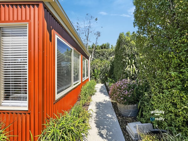 Lush landscaping surrounds this vibrant home, featuring a welcoming pathway and abundant greenery for outdoor enjoyment.