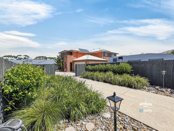 Discover a welcoming entrance lined with greenery, leading to a spacious home in a peaceful neighborhood.