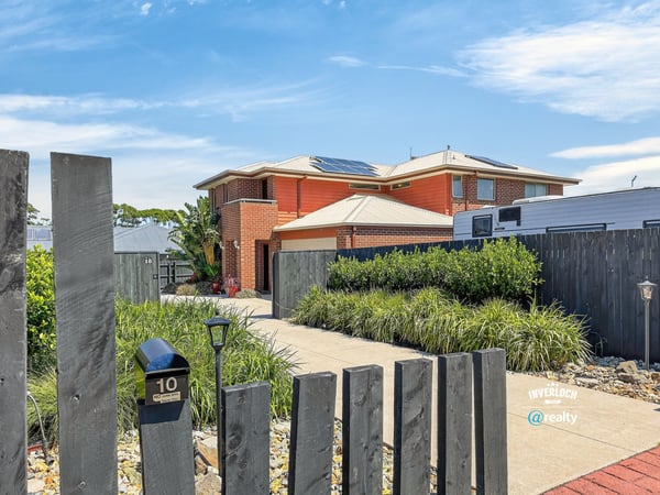 Modern home featuring solar panels, lush landscaping, and a welcoming pathway in a desirable neighborhood.