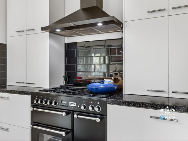 Modern kitchen featuring sleek cabinetry, a gas range, and a striking mirrored backsplash for added depth.