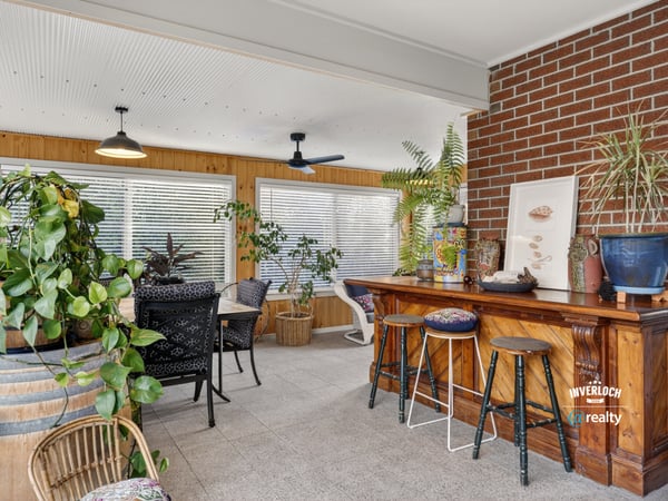 Bright sunroom featuring a cozy bar, abundant greenery, and ample natural light for relaxation and entertainment.