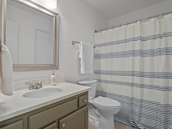 Updated hall bath with painted vanity, quartz countertop, new light fixture and new mirror