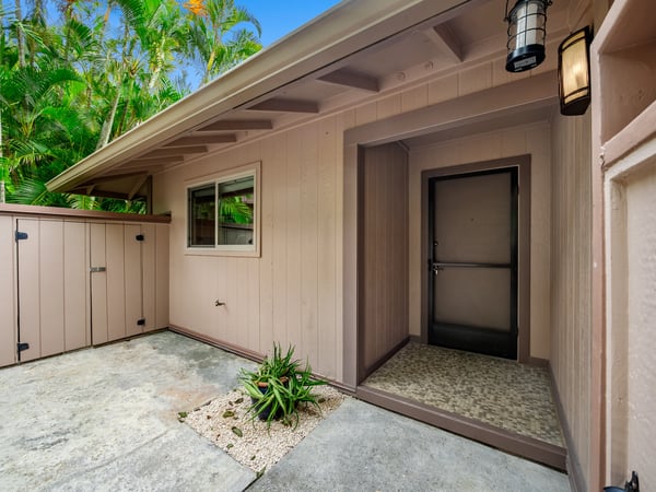 Welcoming entrance featuring unique architectural details, surrounded by lush landscaping and a private outdoor space.