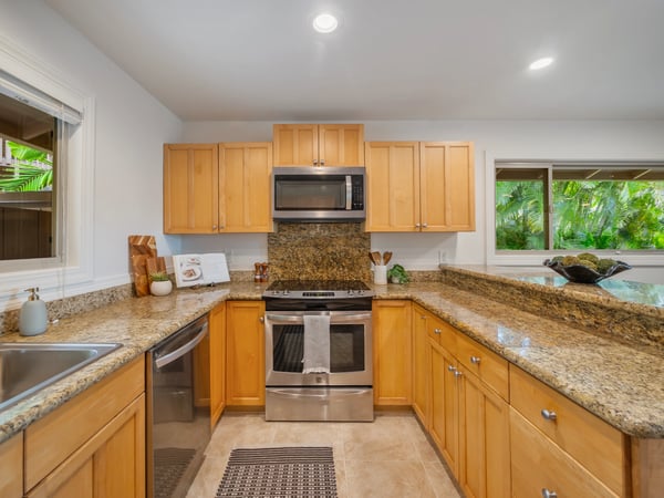 This inviting kitchen features modern appliances, ample counter space, and views of lush greenery.