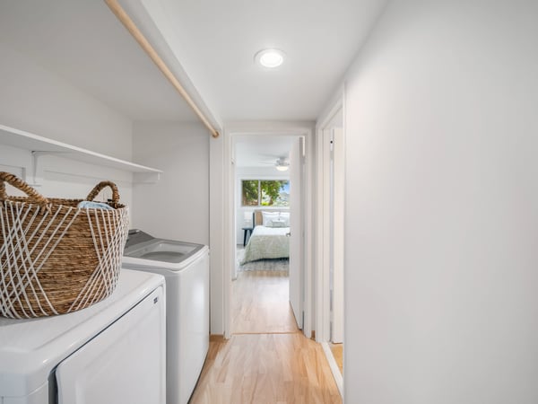 Spacious laundry area leading to a well-lit bedroom, featuring modern appliances and ample storage solutions.