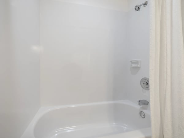 Bright and clean bathtub area featuring a modern showerhead and convenient wall-mounted essentials.