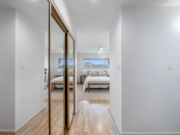Bright and airy corridor leads to a spacious bedroom with mountain views and abundant natural light.