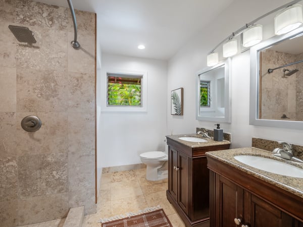 Modern bathroom featuring dual sinks, a spacious walk-in shower, and natural light from adjacent windows.