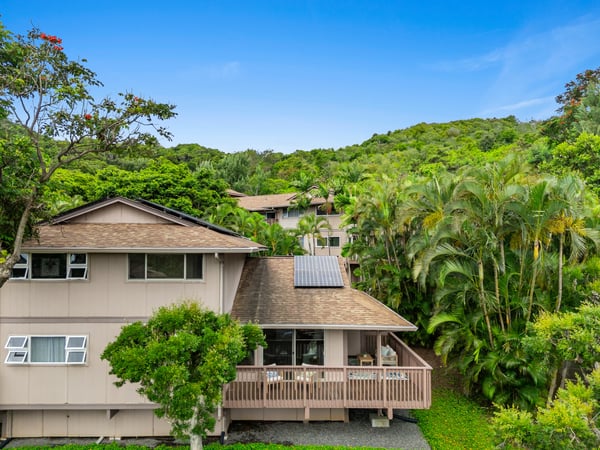 Nestled among lush greenery, this spacious home features a large deck and modern solar energy system.