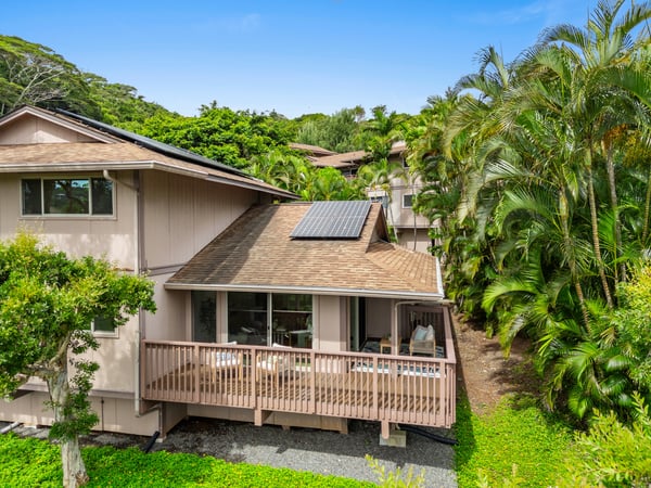 Welcoming home surrounded by lush greenery, featuring a spacious deck and sustainable solar energy options.