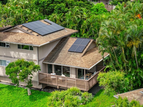 Discover this modern home featuring solar panels and a spacious deck, surrounded by lush tropical landscaping.