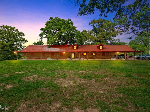 Discover this spacious home set on a sprawling green lot, featuring a distinctive red roof and open outdoor space.