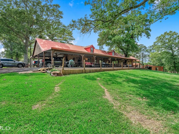 Spacious property featuring a large covered porch, surrounded by lush greenery and scenic views.