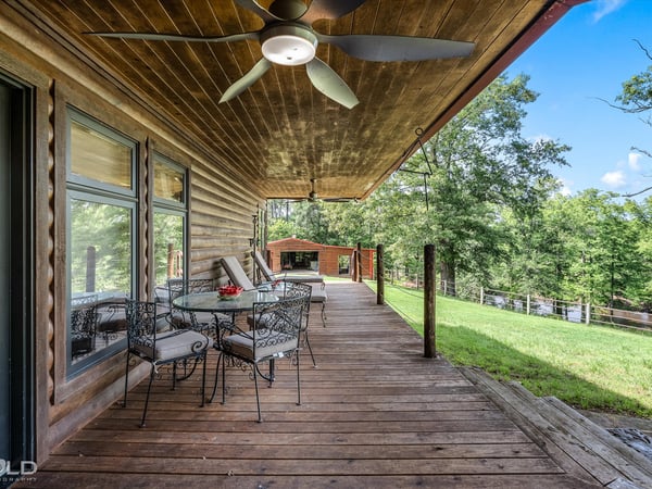 Spacious covered porch with ample seating, perfect for enjoying panoramic views of the surrounding landscape.