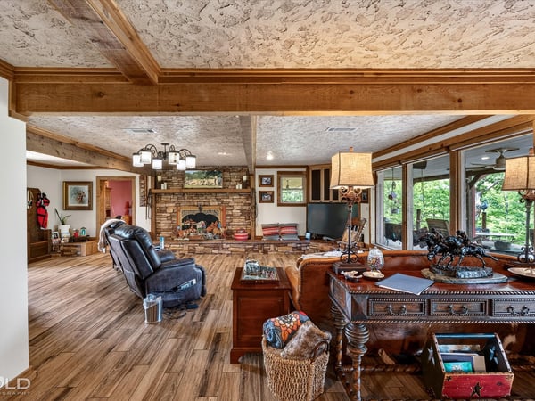 Spacious living area with a rustic fireplace, natural light, and inviting views of the outdoors.