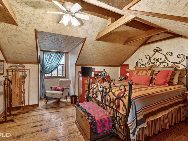 Cozy loft bedroom featuring exposed beams, a unique design, and ample natural light from large windows.
