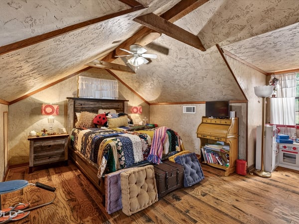Cozy attic bedroom featuring unique rustic decor, ample natural light, and inviting wooden accents throughout.