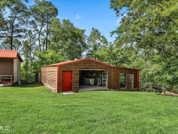 Spacious outdoor area featuring a large storage barn surrounded by lush greenery and trees.