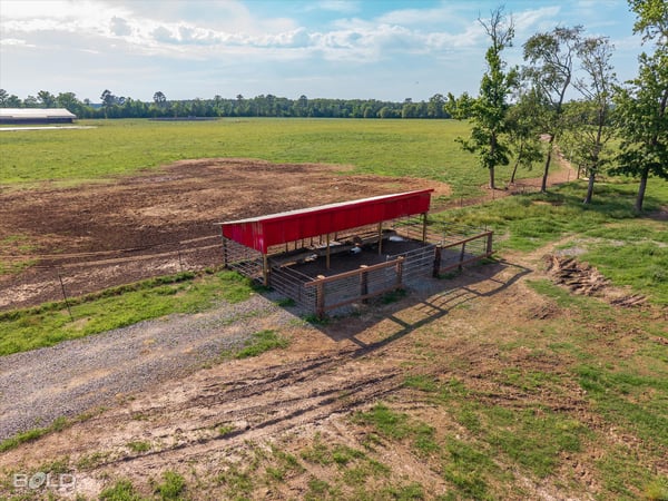 Versatile property featuring a spacious open field with a covered structure, perfect for agricultural or recreational use.