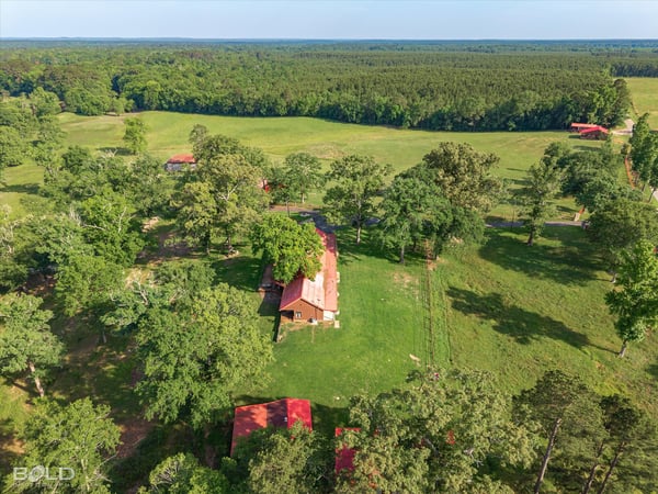 Spacious property featuring a cozy home surrounded by lush greenery and expansive fields, perfect for outdoor enthusiasts.