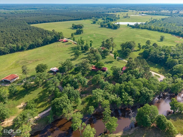 Expansive rural property featuring lush pastures, scenic water views, and multiple outbuildings for versatile use.