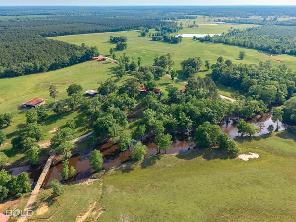 Expansive countryside property featuring lush greenery, flowing water, and ample space for outdoor activities and development.