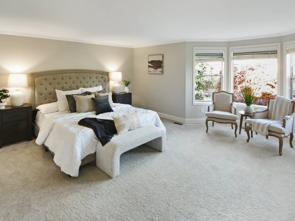 Spacious bedroom features large windows and cozy seating, perfect for relaxation and natural light.