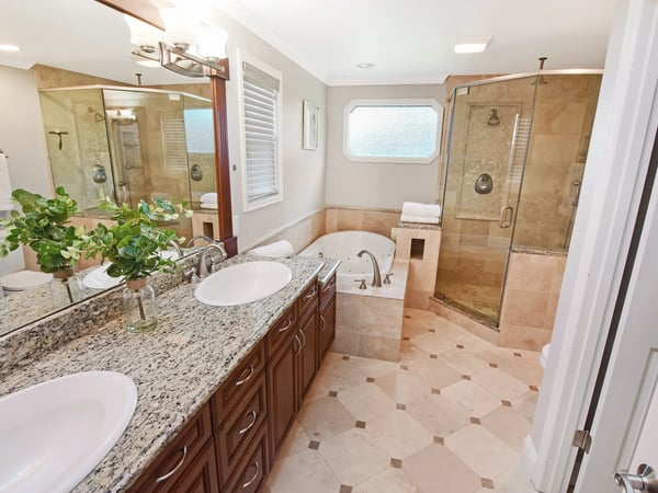 This sophisticated bathroom features modern amenities, dual vanities, a spacious shower, and a relaxing tub area.