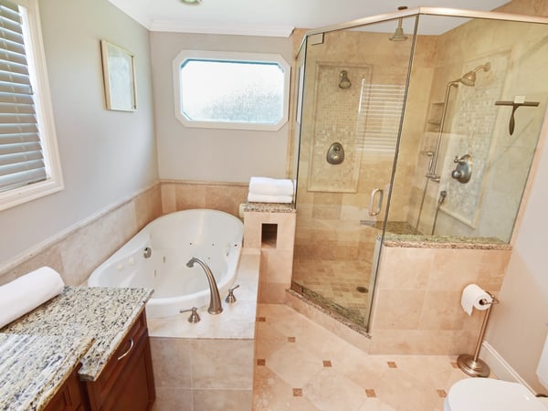 Modern bathroom featuring a spacious soaking tub, glass-enclosed shower, and sleek granite surfaces for a luxurious experience.