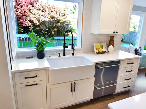 Bright kitchen featuring a farmhouse sink, modern fixtures, and abundant natural light with garden views.