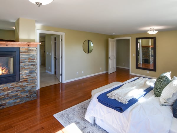 Spacious bedroom featuring a cozy fireplace, modern finishes, and convenient access to adjoining rooms.
