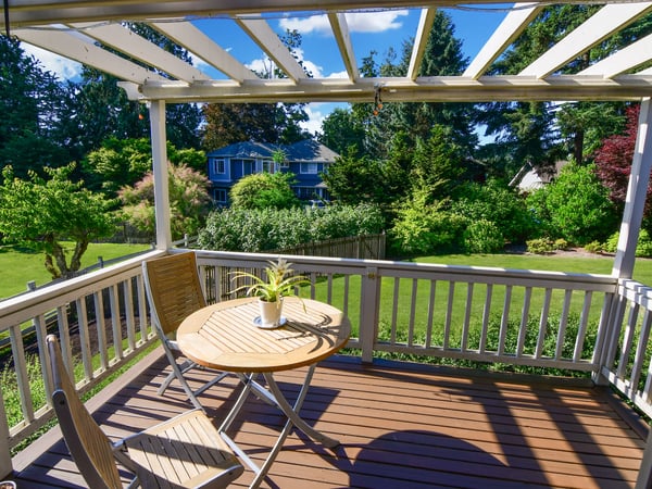 Sunny porch overlooking a spacious backyard, perfect for outdoor dining and relaxation.