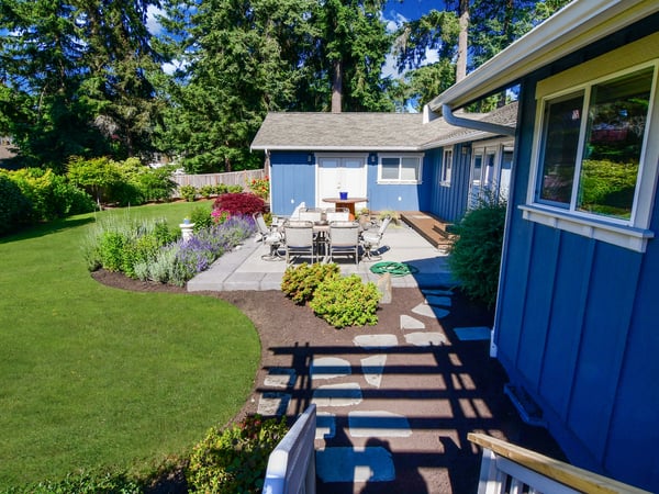 Spacious backyard featuring a stone patio, perfect for outdoor dining and entertaining amidst lush landscaping.