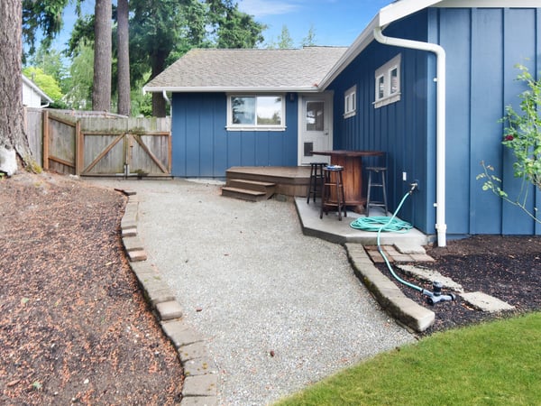 This inviting outdoor space features a gravel pathway, surrounded by landscaping, perfect for relaxation and gatherings.