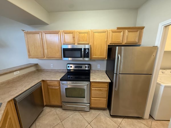 Kitchen equipped with stainless steel appliances, abundant cabinetry, and easy-care tile flooring. The efficient layout maximizes workspace and storage.