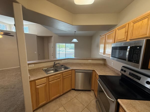 Bright kitchen with breakfast bar seating, stainless steel appliances, and dual-basin sink. The open floor plan creates a seamless connection to the living and dining areas.
