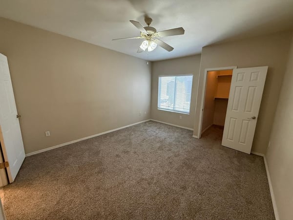 Spacious bedroom with neutral finishes, plush carpeting, ceiling fan, and natural light. A peaceful retreat designed for relaxation and everyday comfort.