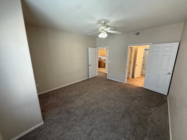 Large bedroom offering easy access to the bathroom and walk-in closet. Soft carpeting and neutral tones create a warm and inviting atmosphere.