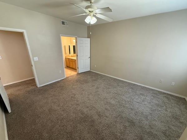Well-sized bedroom featuring ceiling fan, comfortable carpeting, and convenient access to adjacent living spaces. Ideal for creating a relaxing personal retreat.