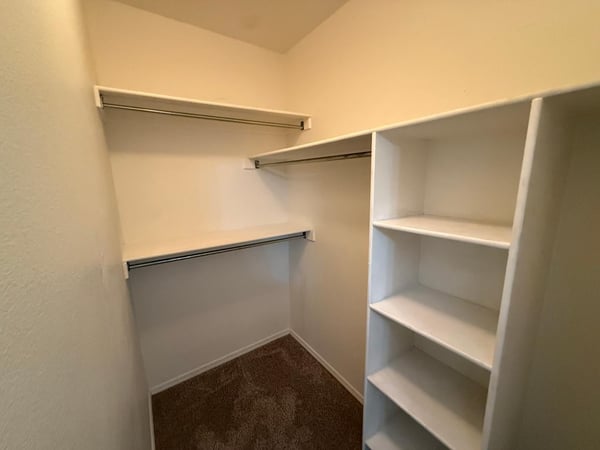 Spacious walk-in closet with built-in shelving and multiple storage options. Designed to maximize organization while providing plenty of room for clothing and accessories.