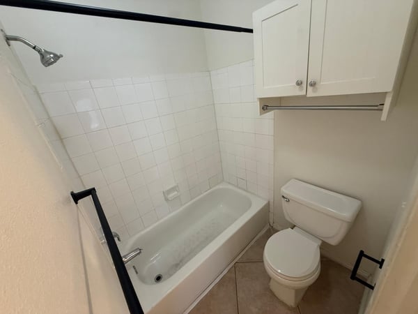 Full bathroom with tub and shower combination, tile surround, built-in storage, and easy-care flooring. The clean, neutral design complements the updated interior of this Phoenix residence.