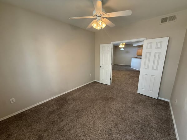 Comfortable secondary bedroom offering soft carpeting, ceiling fan, neutral paint tones, and generous floor space. A versatile addition to this well-maintained Phoenix property.