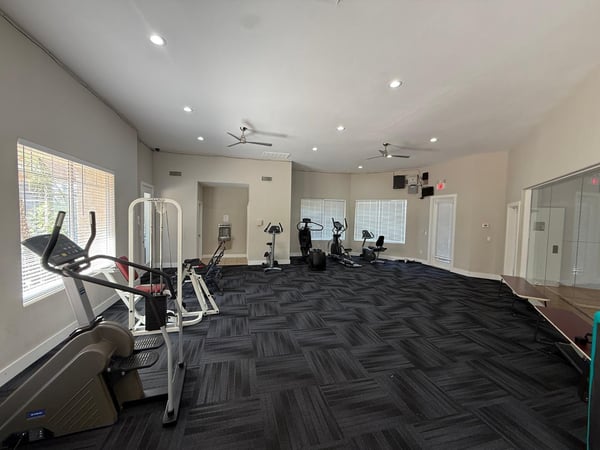 Open fitness center showcasing multiple workout stations, cardio machines, and bright interior spaces. This Phoenix community provides convenient wellness amenities for residents seeking an active lifestyle.